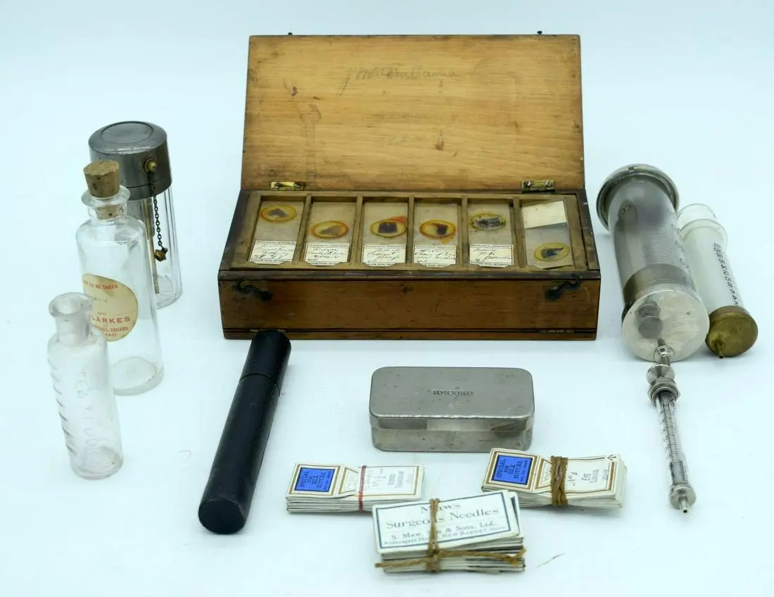 A collection of vintage medical syringes, thermometer